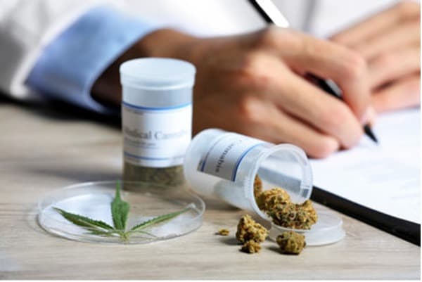 A doctor writing a prescription with two pill bottles of medical marijuana in front of him.