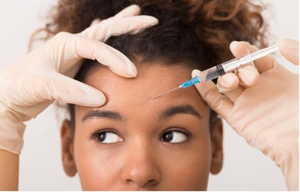 Girl receiving botox injection in her forehead.
